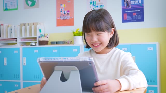 Shot in elementary school, girl student brightly smiling while looking at digital textbook in class / South Korea 동영상 (JKR250785) - 게티이미지뱅크